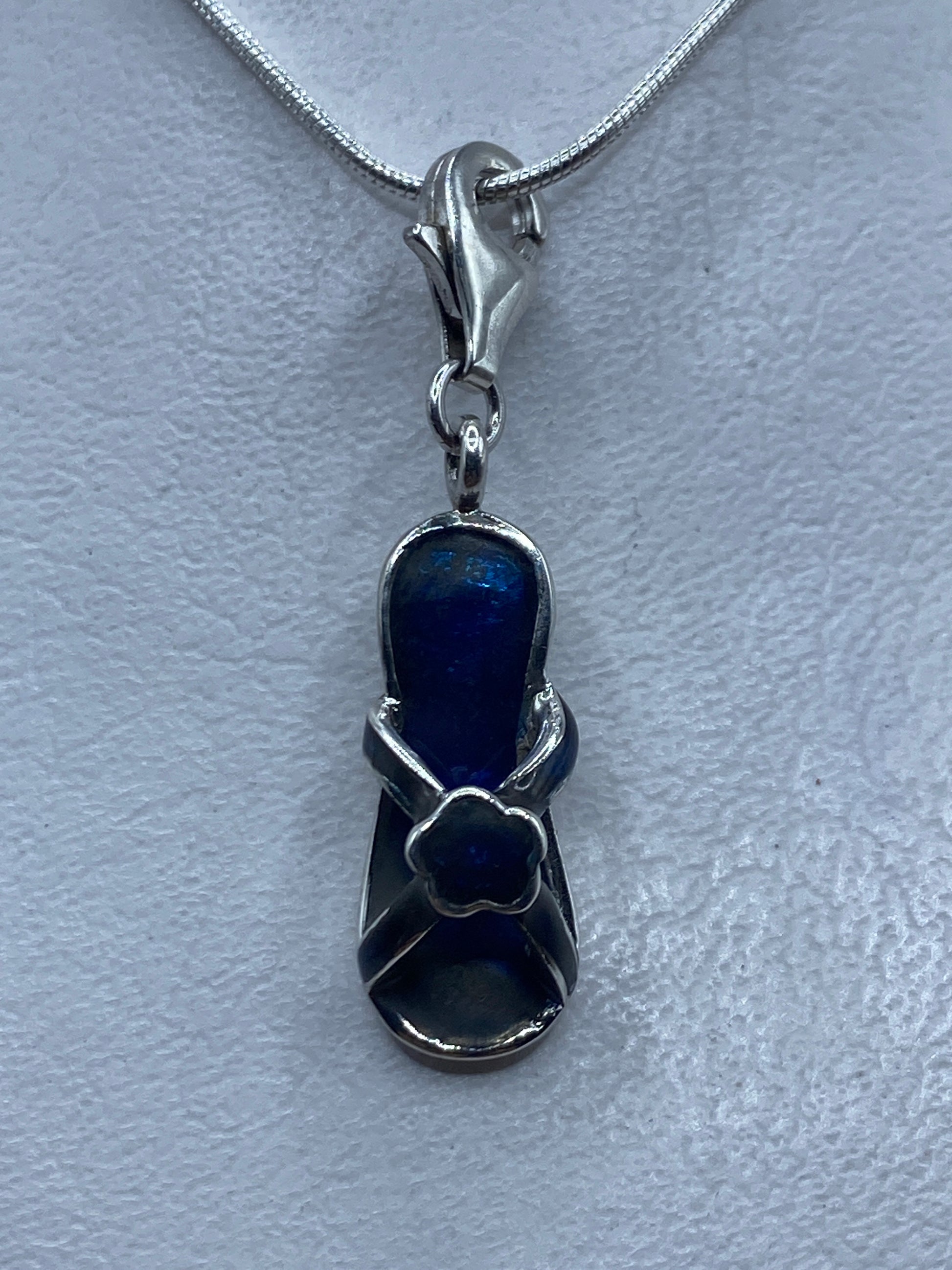 Dije de plata .925 con piedra azul engastada, colgando de cadena plateada