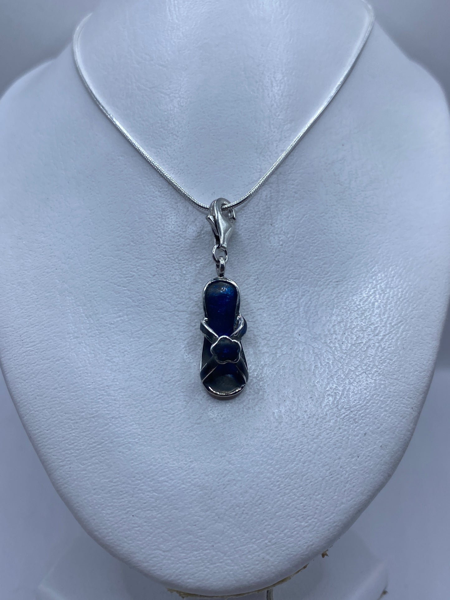 Dije de 4.1 cm de largo con piedra azul en primer plano sobre pecho de mujer