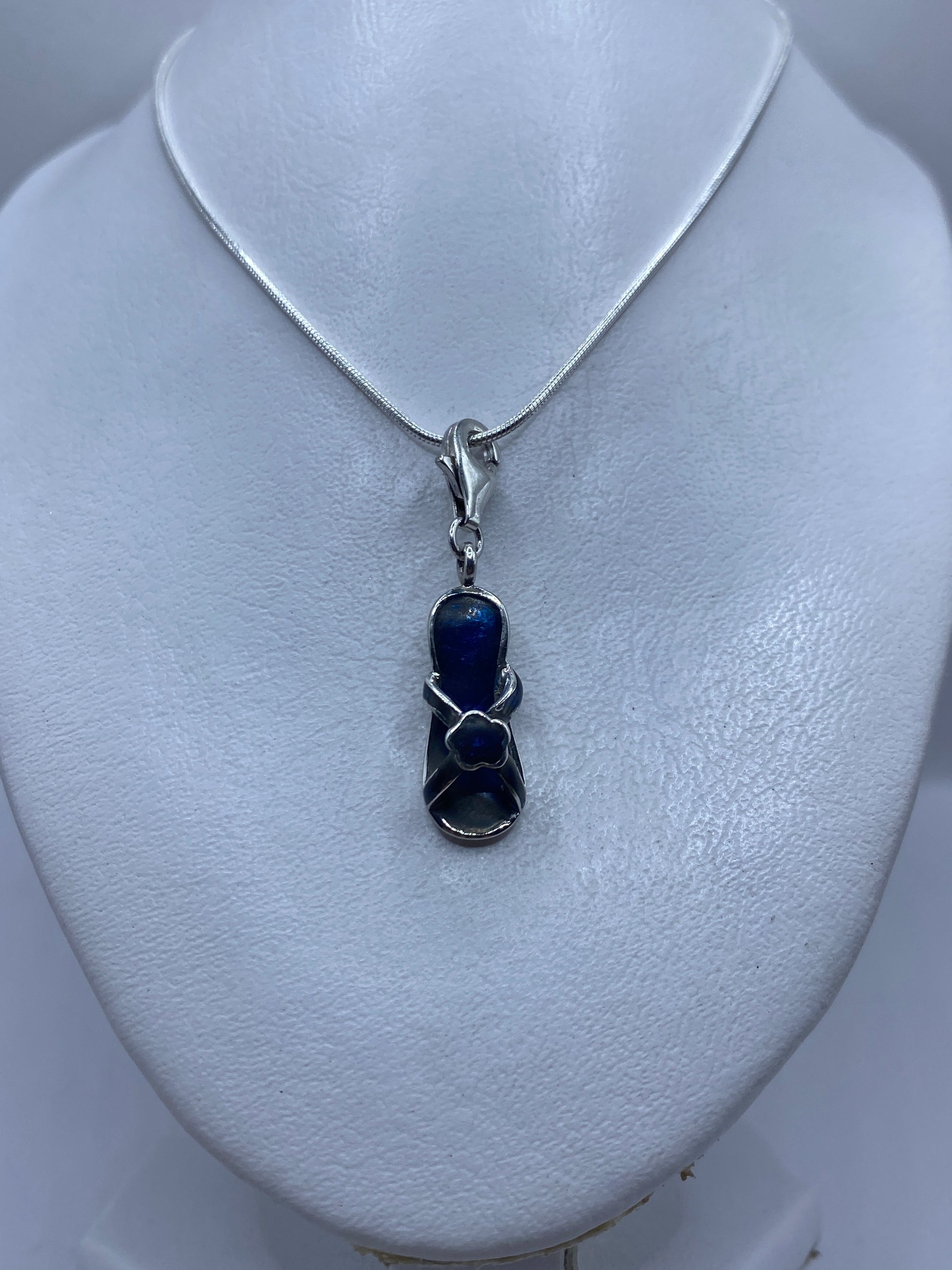Dije de 4.1 cm de largo con piedra azul en primer plano sobre pecho de mujer