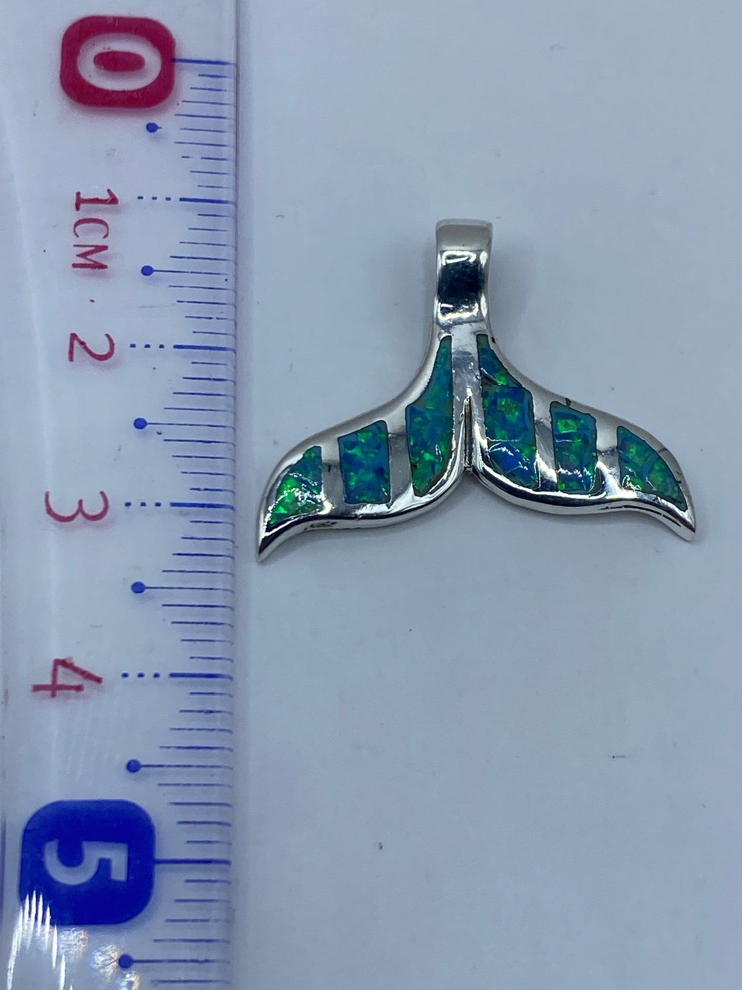 Medida del dije de 3.6 cm de largo junto a regla métrica