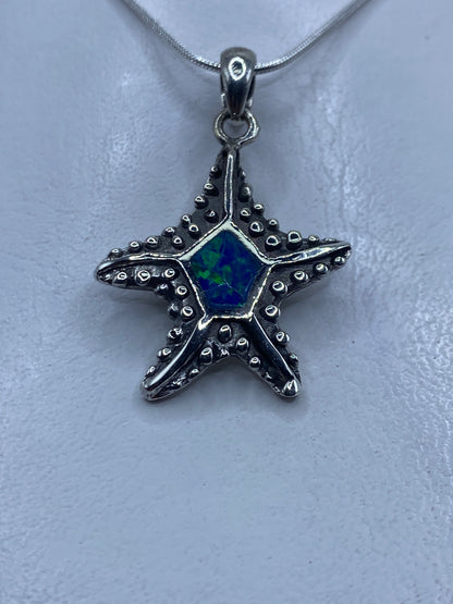 Dije de plata en forma de estrella marina con ópalo de fuego azul en el centro