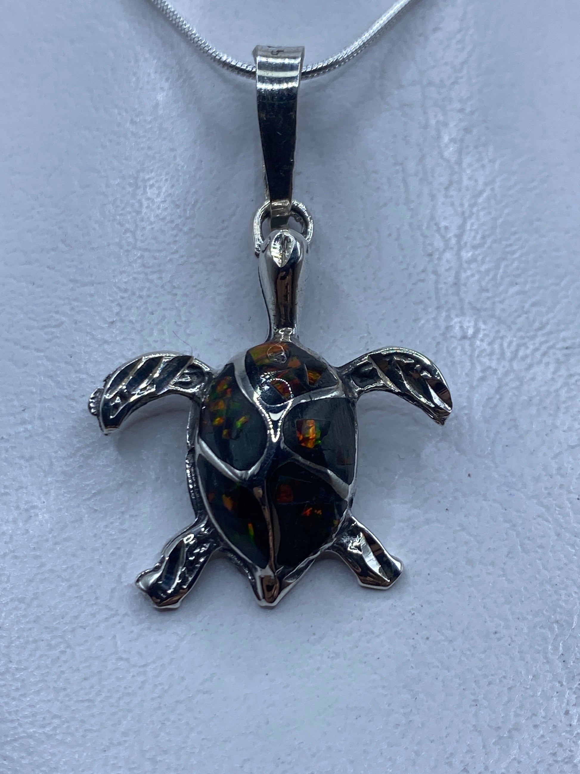 Dije de tortuga en plata .925 con ópalo de fuego multicolor, colgado de una cadena de plata
