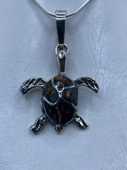 Dije de tortuga en plata .925 con ópalo de fuego multicolor, colgado de una cadena de plata