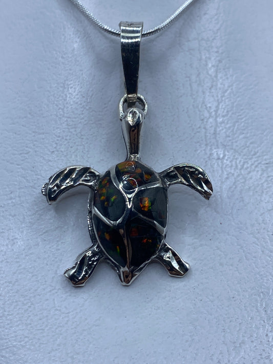 Dije de tortuga en plata .925 con ópalo de fuego multicolor, colgado de una cadena de plata