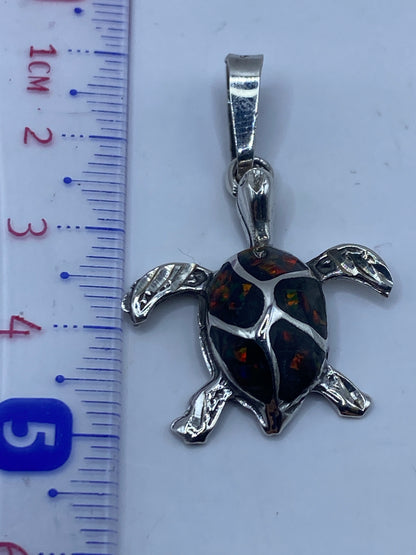 Dije tortuga sobre fondo blanco junto a regla, mostrando 4.7 cm de largo
