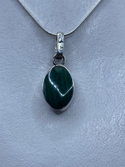 Detalle del dije mostrando el ópalo de fuego natural con reflejos verdes y el engaste de plata