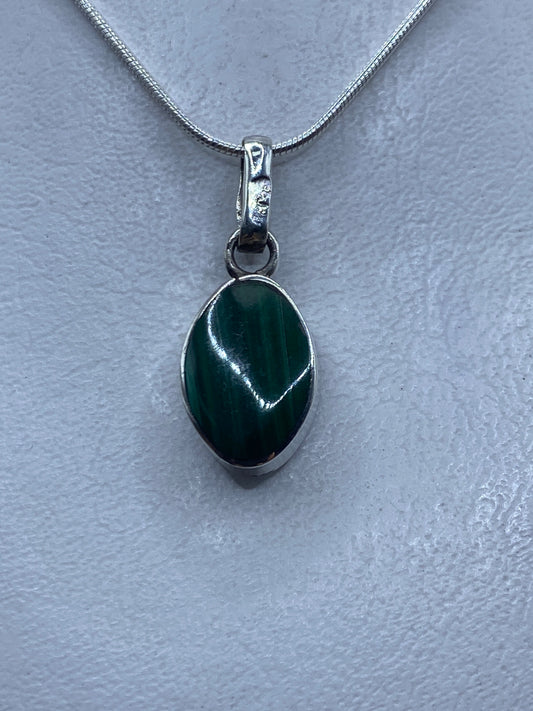 Detalle del dije mostrando el ópalo de fuego natural con reflejos verdes y el engaste de plata