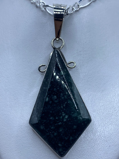 Dije de plata geométrico facetado con piedra, colgando de una cadena de plata brillante