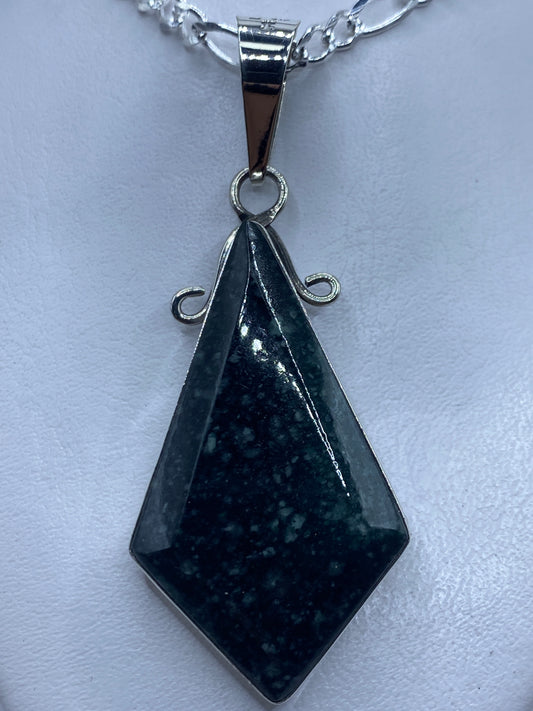 Dije de plata geométrico facetado con piedra, colgando de una cadena de plata brillante