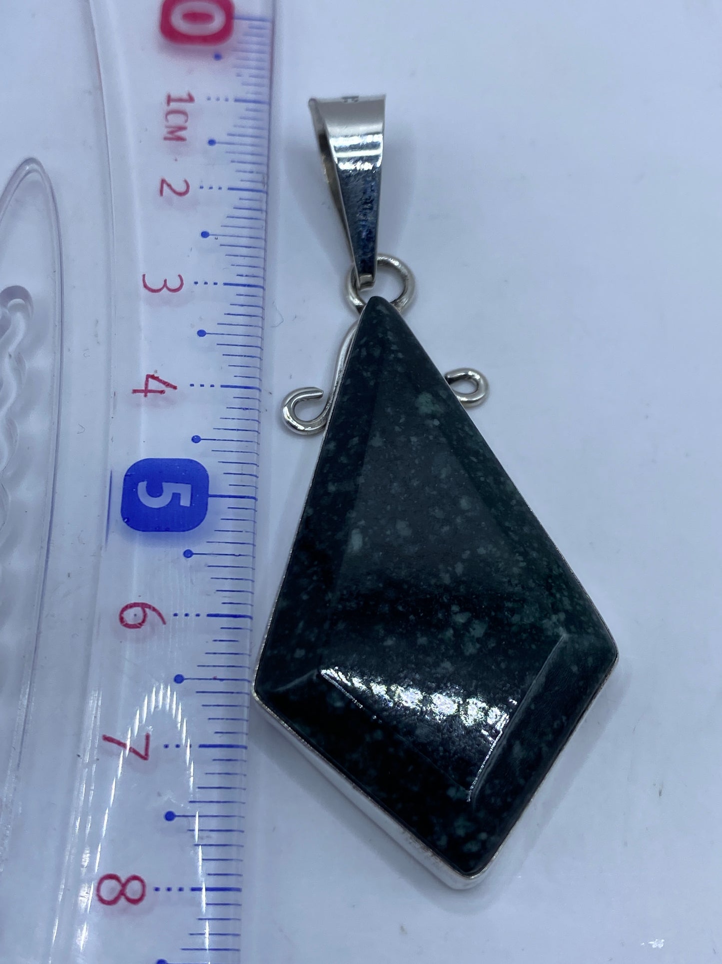 Dije de plata .950 con incrustación de piedra, vista lateral mostrando profundidad y brillo