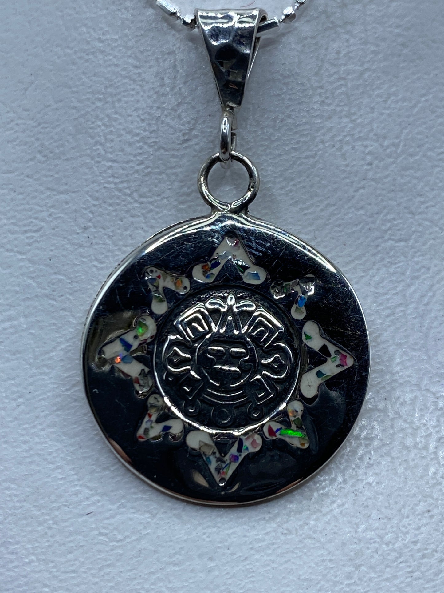 Dije de plata con ópalo de fuego multicolor en diseño de sol prehispánico azteca