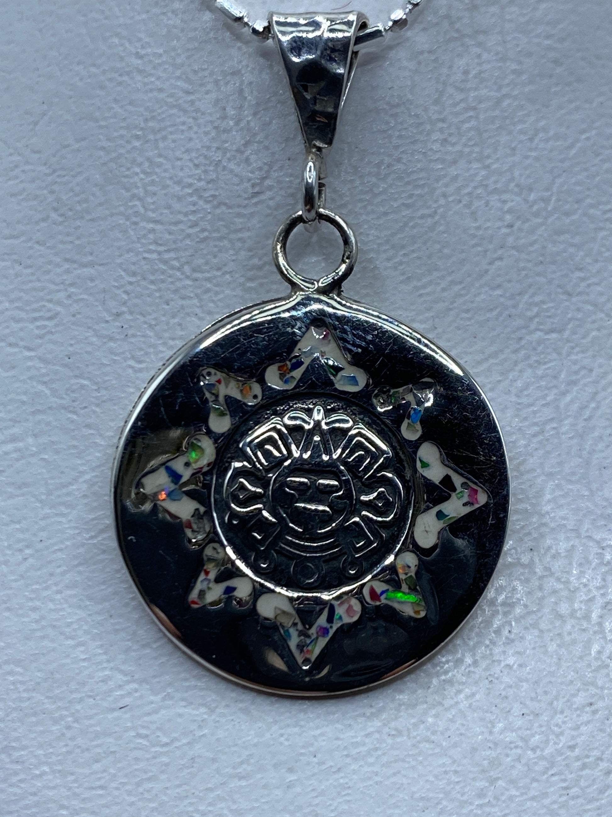 Dije de plata con ópalo de fuego multicolor en diseño de sol prehispánico azteca