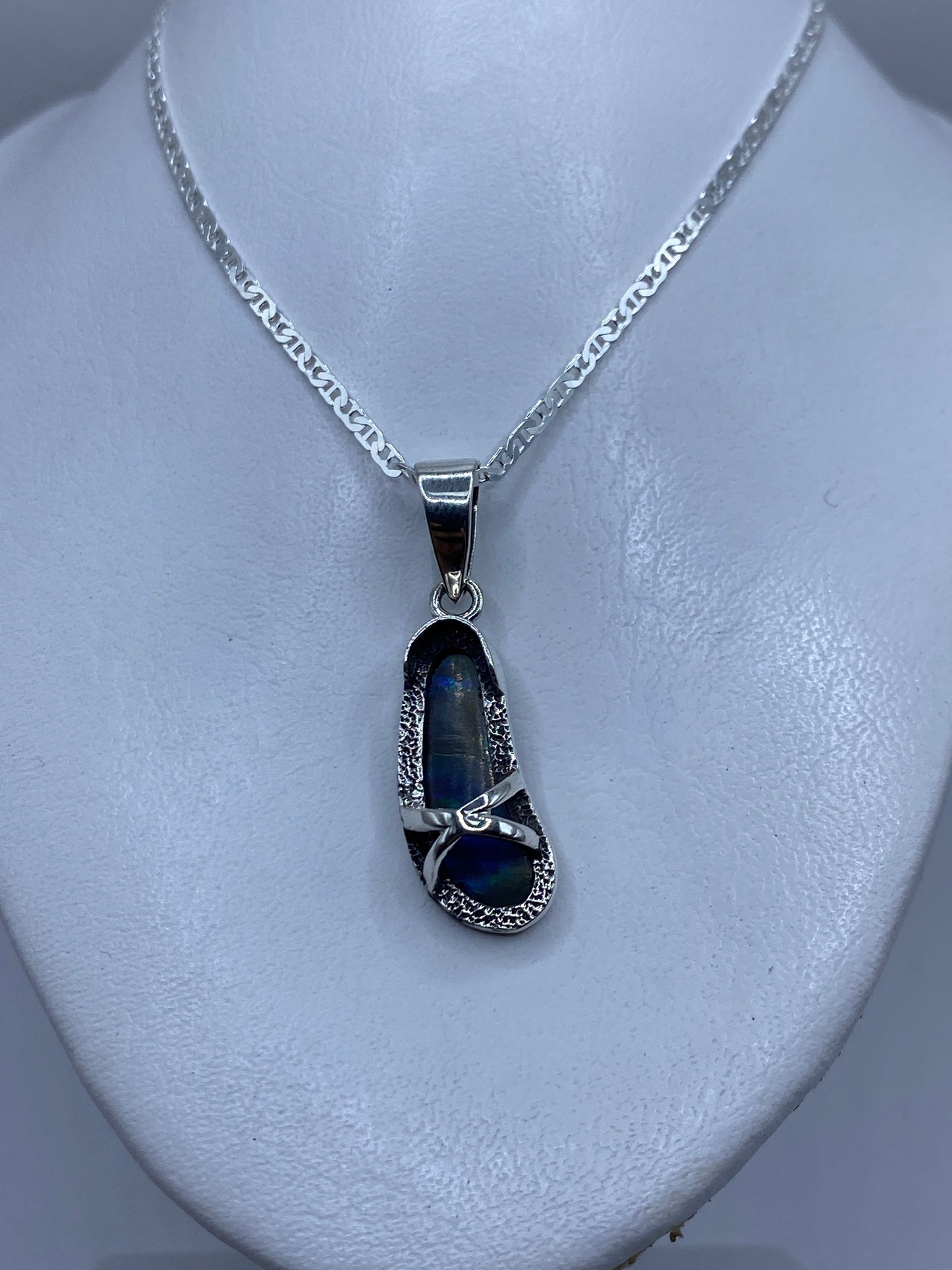 Dije de 4.5 cm sobre el pecho, mostrando el brillo azul del ópalo