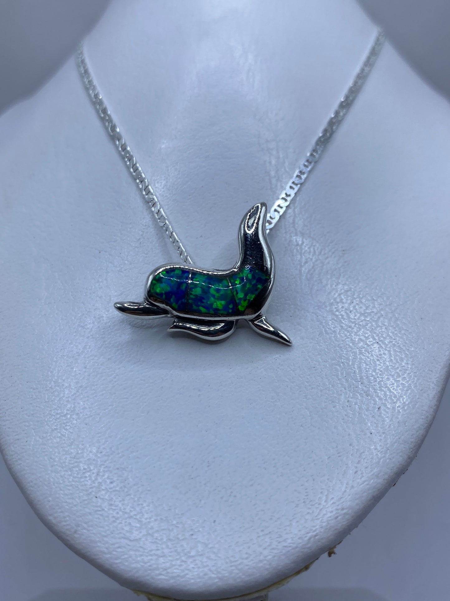 Detalle del delfín mostrando el engaste de piedra azul y el pulido espejo de la plata