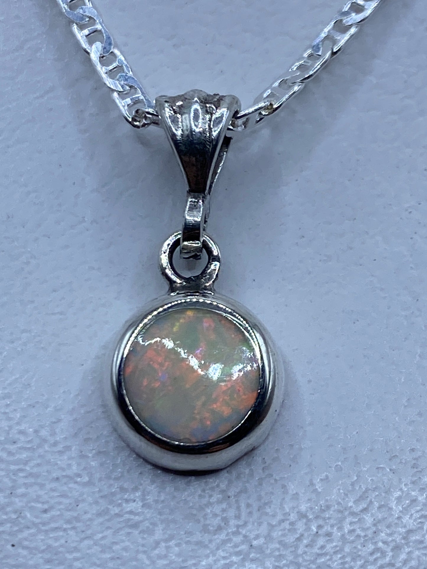 Dije de ópalo de fuego multicolor engastado en plata .950, colgando de cadena plateada