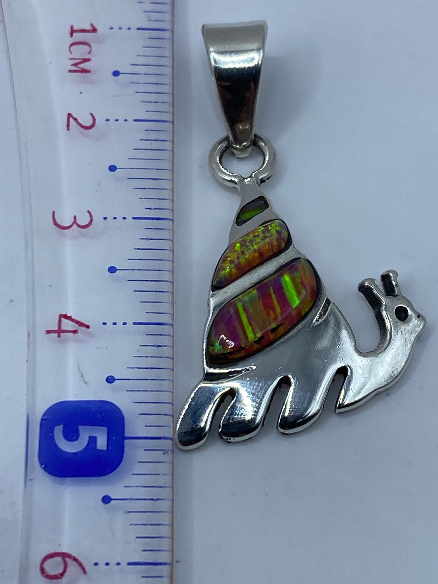 Dije de plata Taxco con ópalo de fuego sobre fondo gris, detalle del engaste