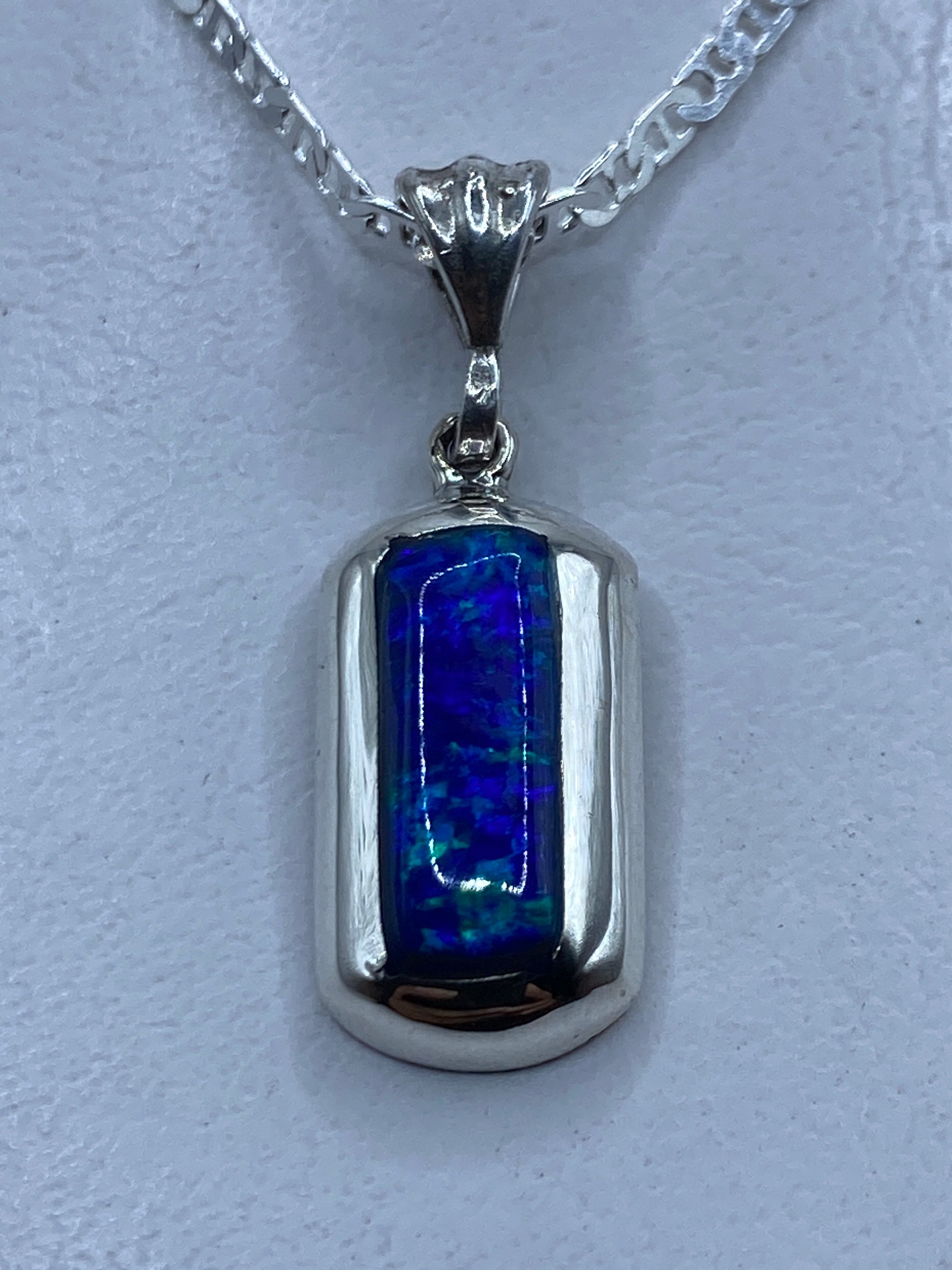 Dije de plata con ópalo de fuego azul colgando de cadena plateada