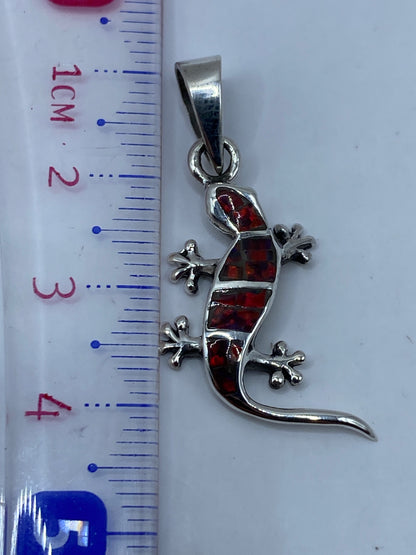 Dije en plata brillante sobre fondo gris, midiendo 4.2 cm de largo, sin cadena