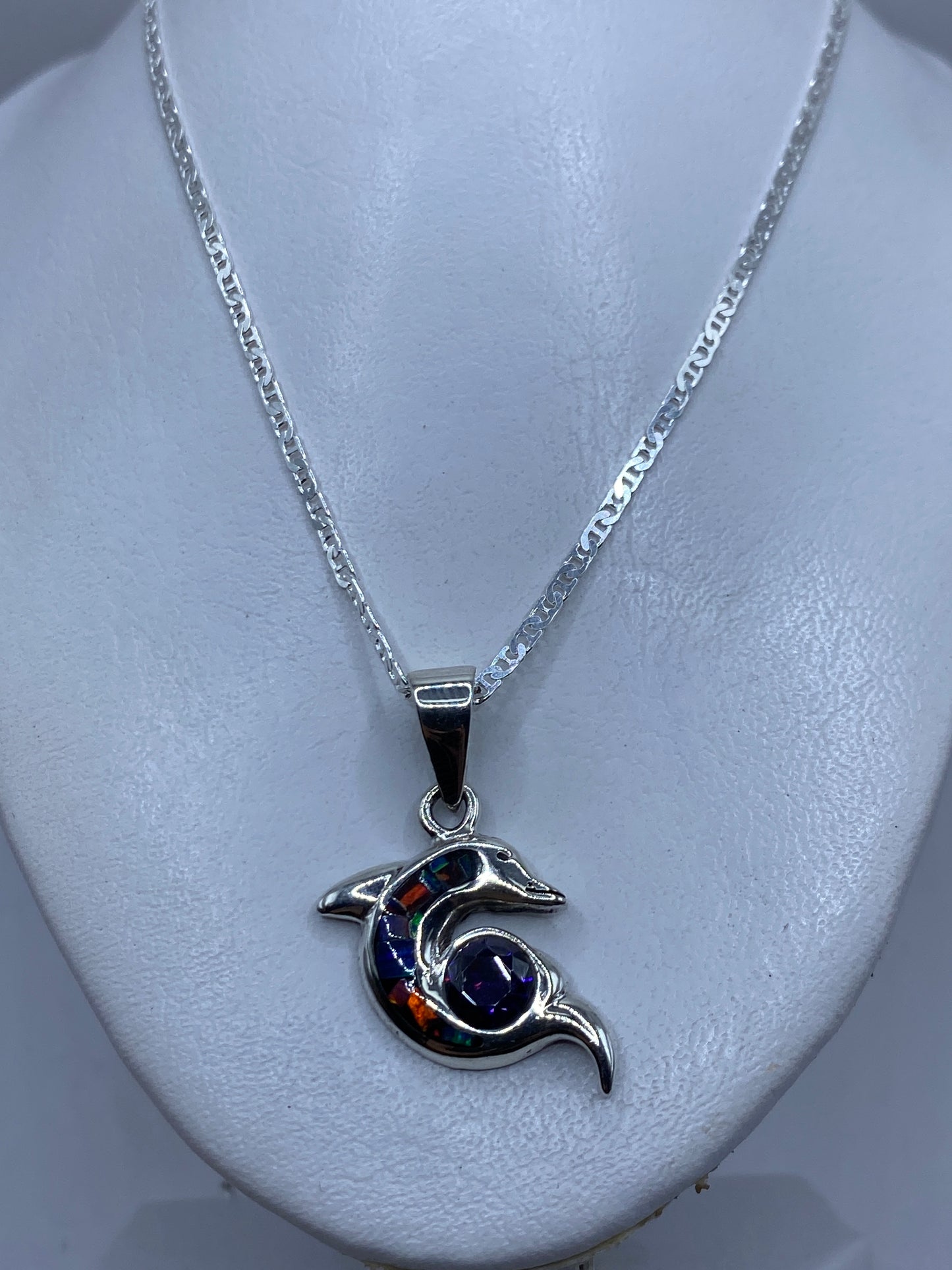 Detalle del delfín de plata mostrando el ópalo de fuego engastado en tonos naranja, azul y verde