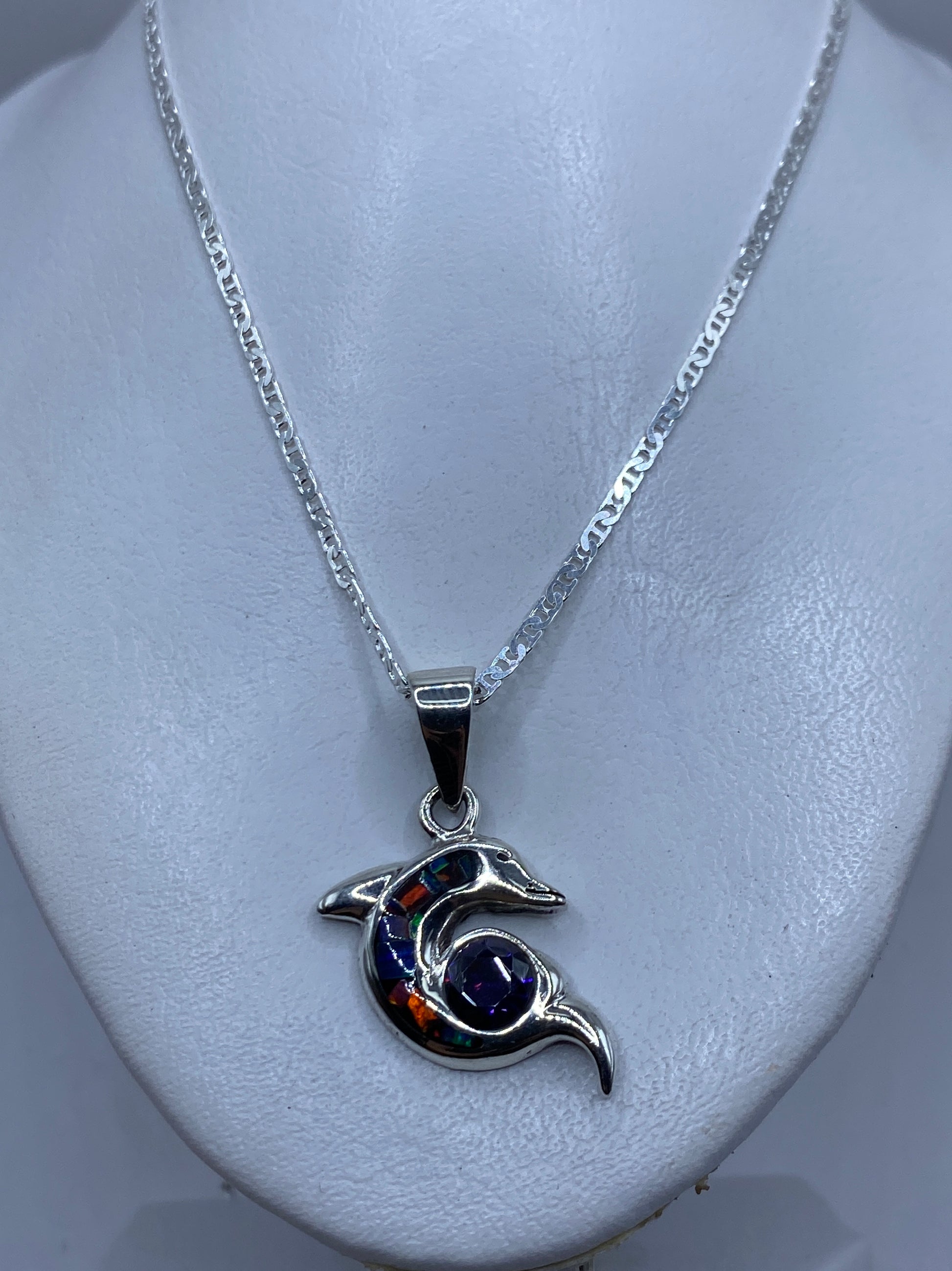 Detalle del delfín de plata mostrando el ópalo de fuego engastado en tonos naranja, azul y verde