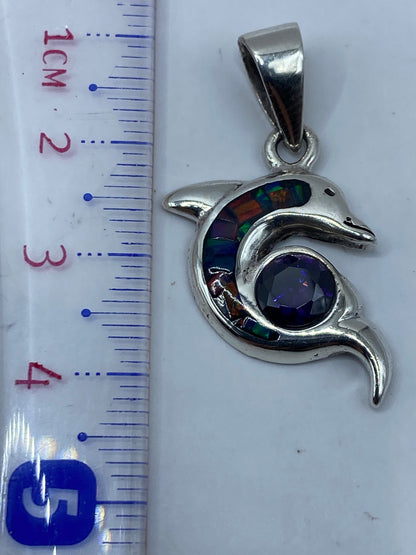 Medida real del dije delfín: 3.7 cm de largo, al lado de una regla