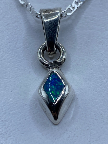 Dije de plata con ópalo de fuego azul en forma de diamante, colgando de cadena de plata