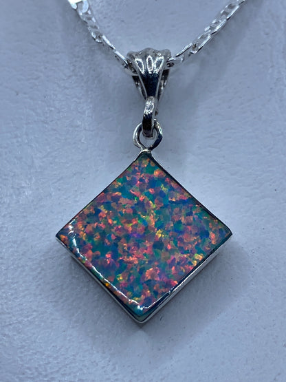 Dije de plata .925 con Ópalo de Fuego engastado, colgante de cadena plateada, mostrando destellos naranja y rojo