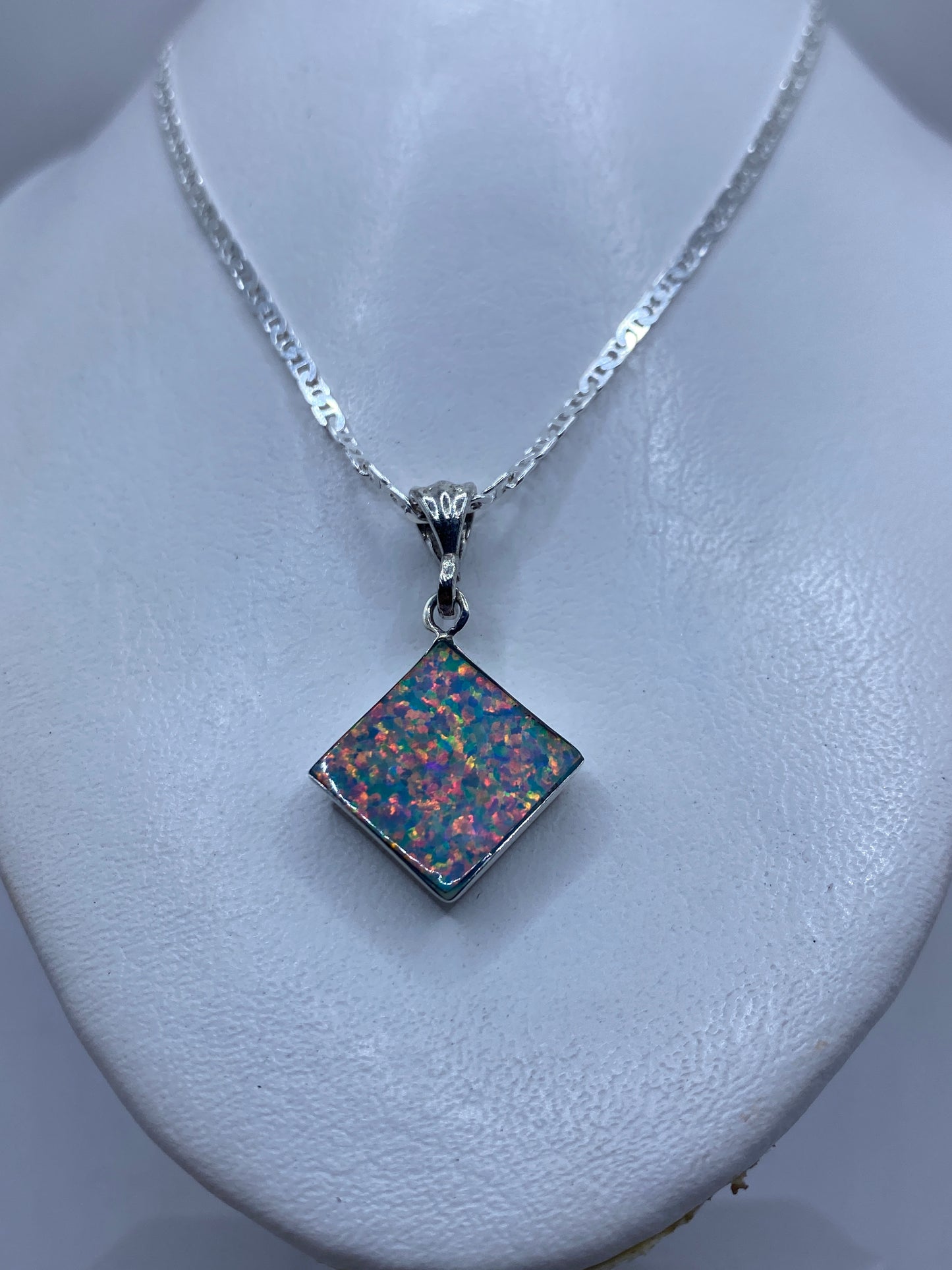 Dije cuadrado de plata con Ópalo de Fuego multicolor sobre piel, con cadena de eslabones gruesos