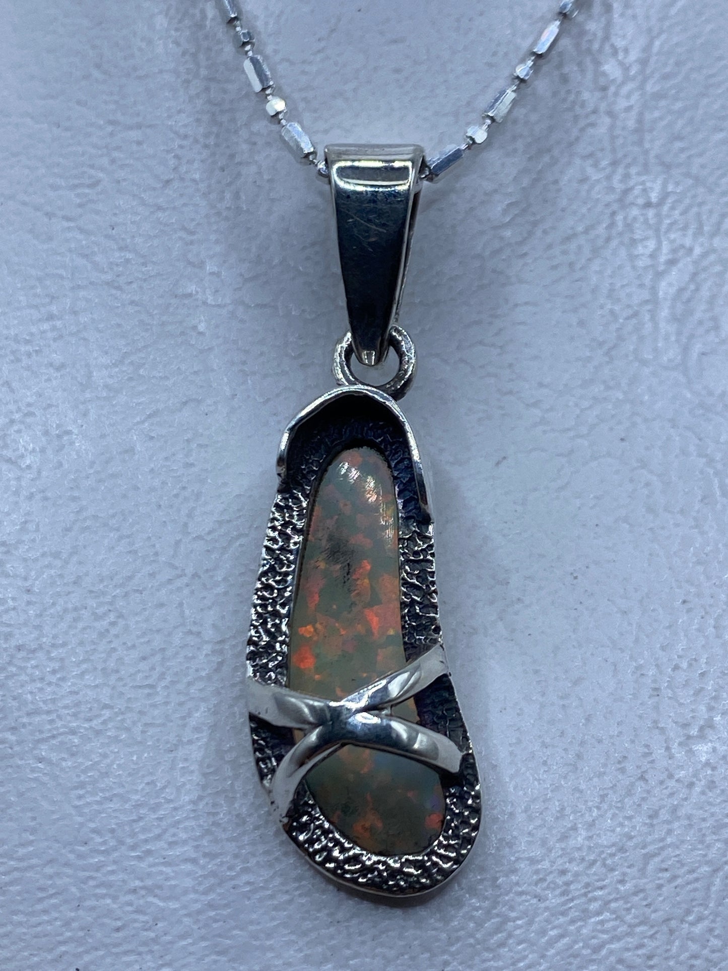 Dije de plata con ópalo de fuego multicolor mostrando reflejos rojos, naranjas y verdes