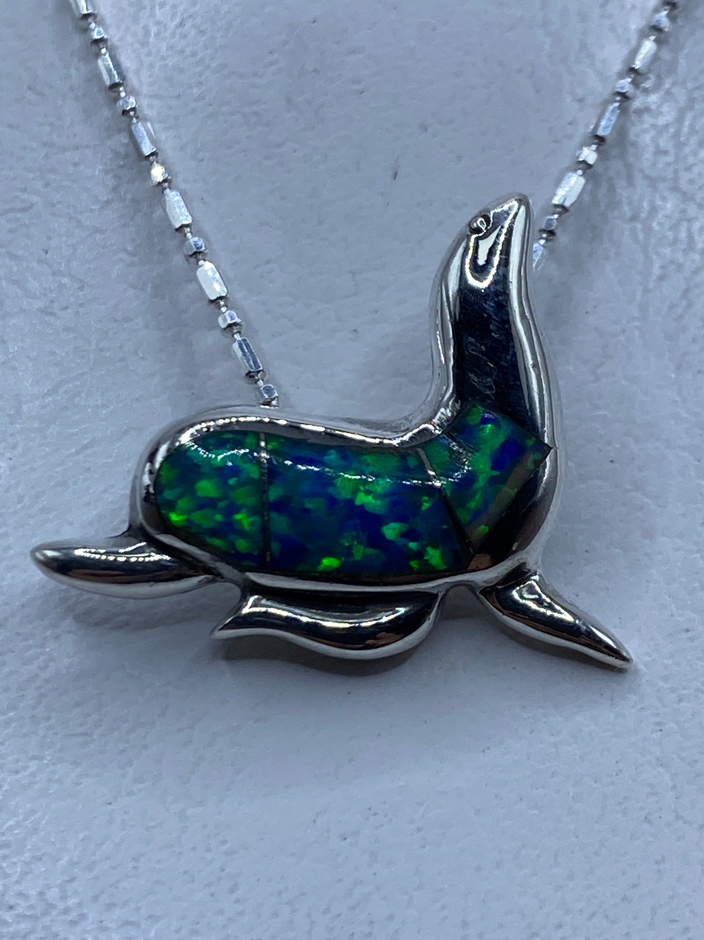 Dije de foca en plata .925 con ópalo de fuego azul, colgando de cadena de eslabón en plata