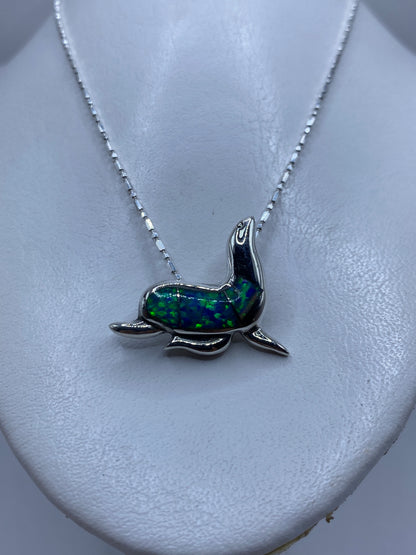 Dije de foca de frente mostrando el ópalo de fuego incrustado en azul vibrante