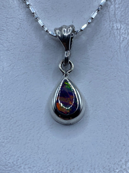 Dije de plata con Opalo de Fuego que refleja tonos naranja y rojo, colgando de una cadena plateada