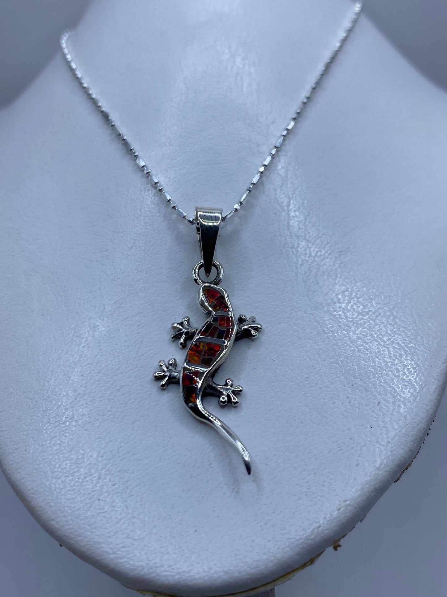 Detalle del ópalo de fuego multicolor en tonos rojo, naranja y amarillo en el dije lagartija