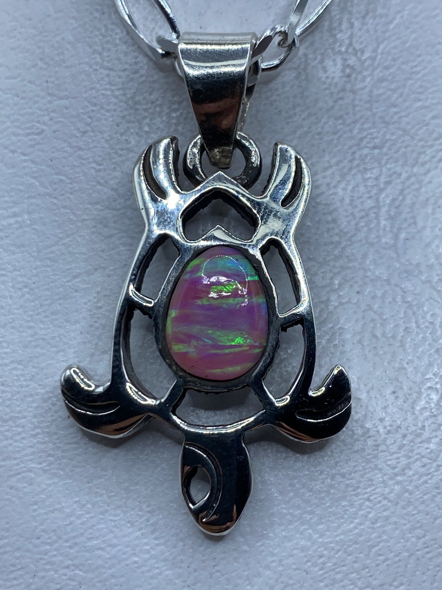Dije de plata .950 con ópalo de fuego rosa, diseño escultural con alas y brazos que abrazan la piedra