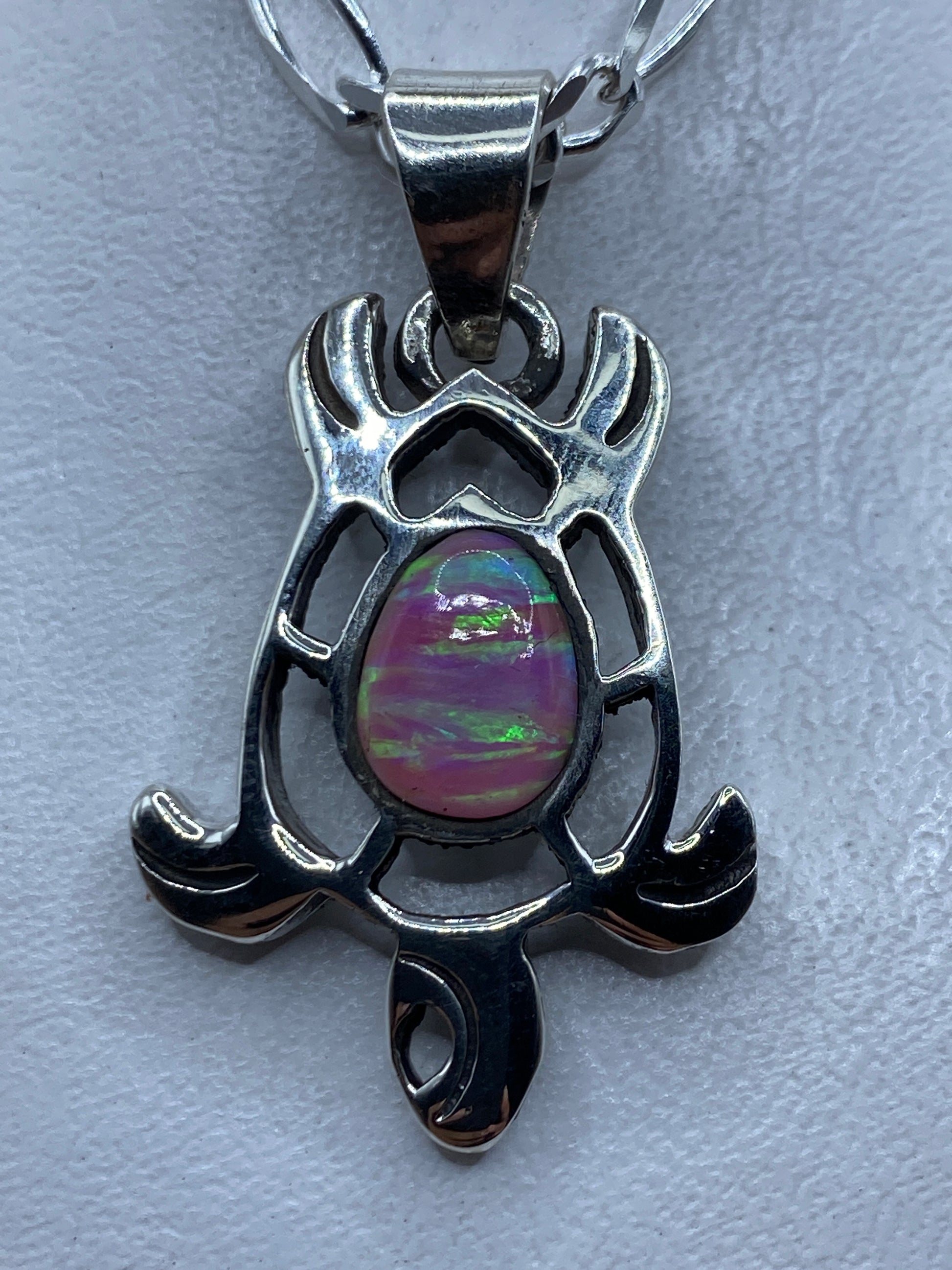 Dije de plata .950 con ópalo de fuego rosa, diseño escultural con alas y brazos que abrazan la piedra