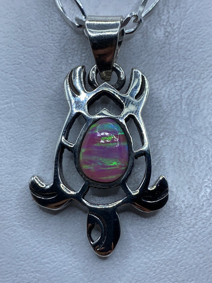Dije de plata .950 con ópalo de fuego rosa, diseño escultural con alas y brazos que abrazan la piedra