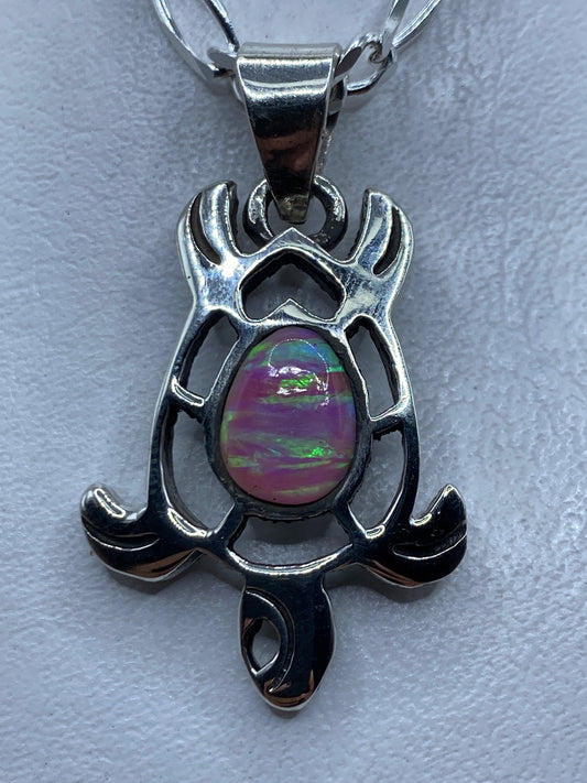 Dije de plata .950 con ópalo de fuego rosa, diseño escultural con alas y brazos que abrazan la piedra