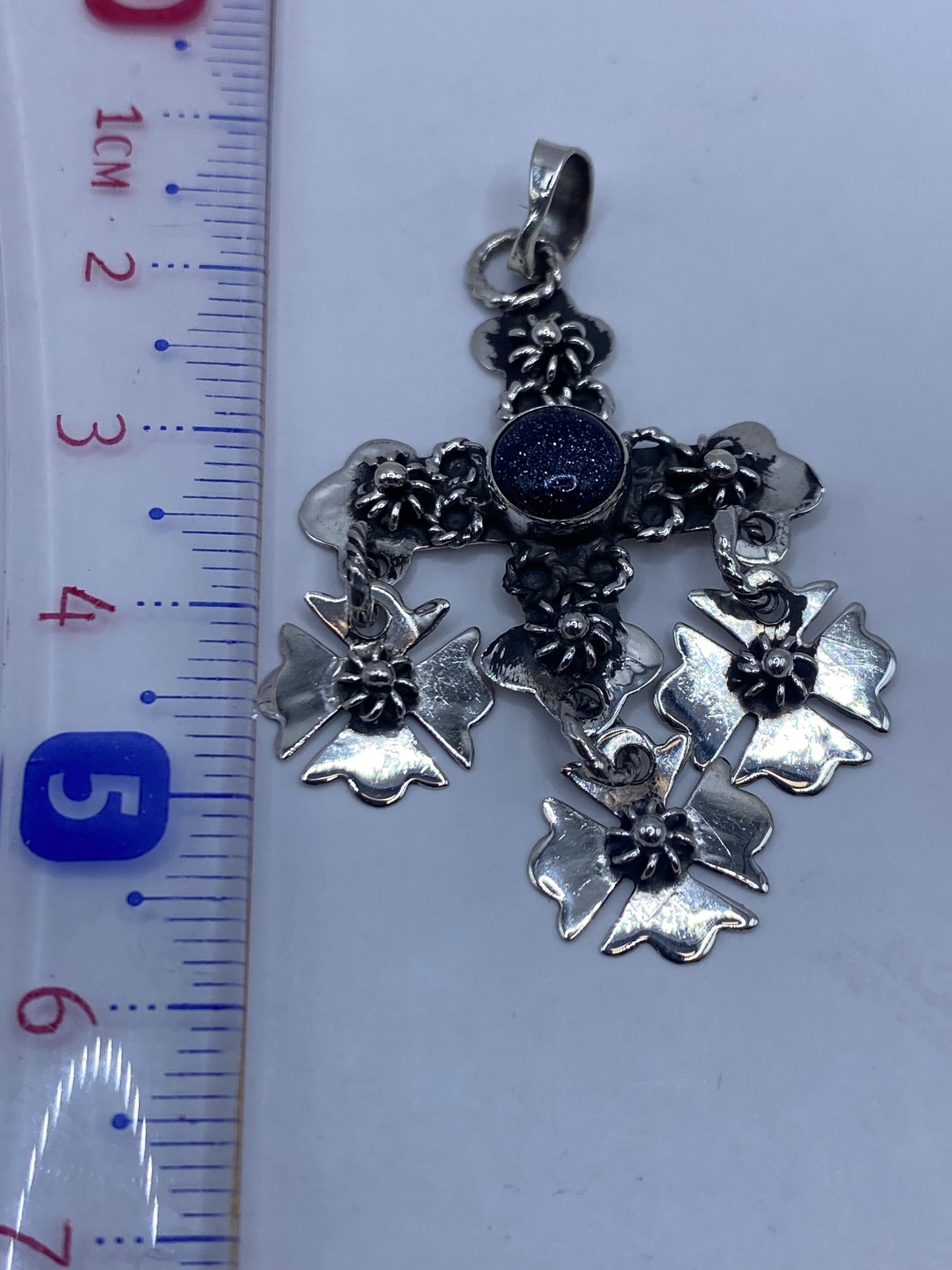 Dije cruz de plata Taxco sobre regla, midiendo 5.7 cm de largo