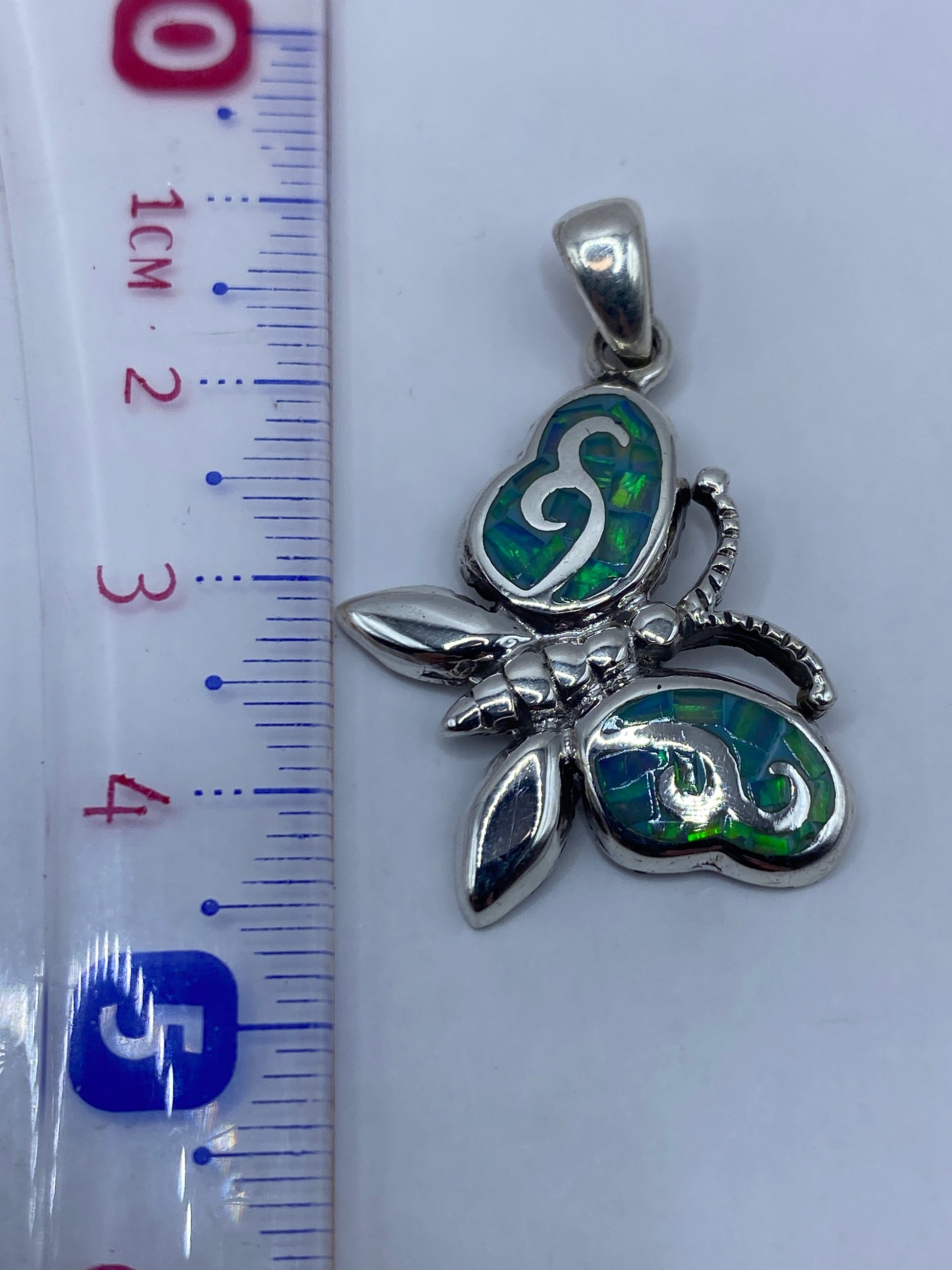Medición del dije mariposa con regla: 4.5 cm de largo, pieza compacta y elegante
