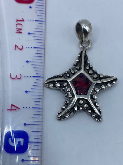 Dije de estrella de mar colocado sobre una regla mostrando 4.4 cm de largo