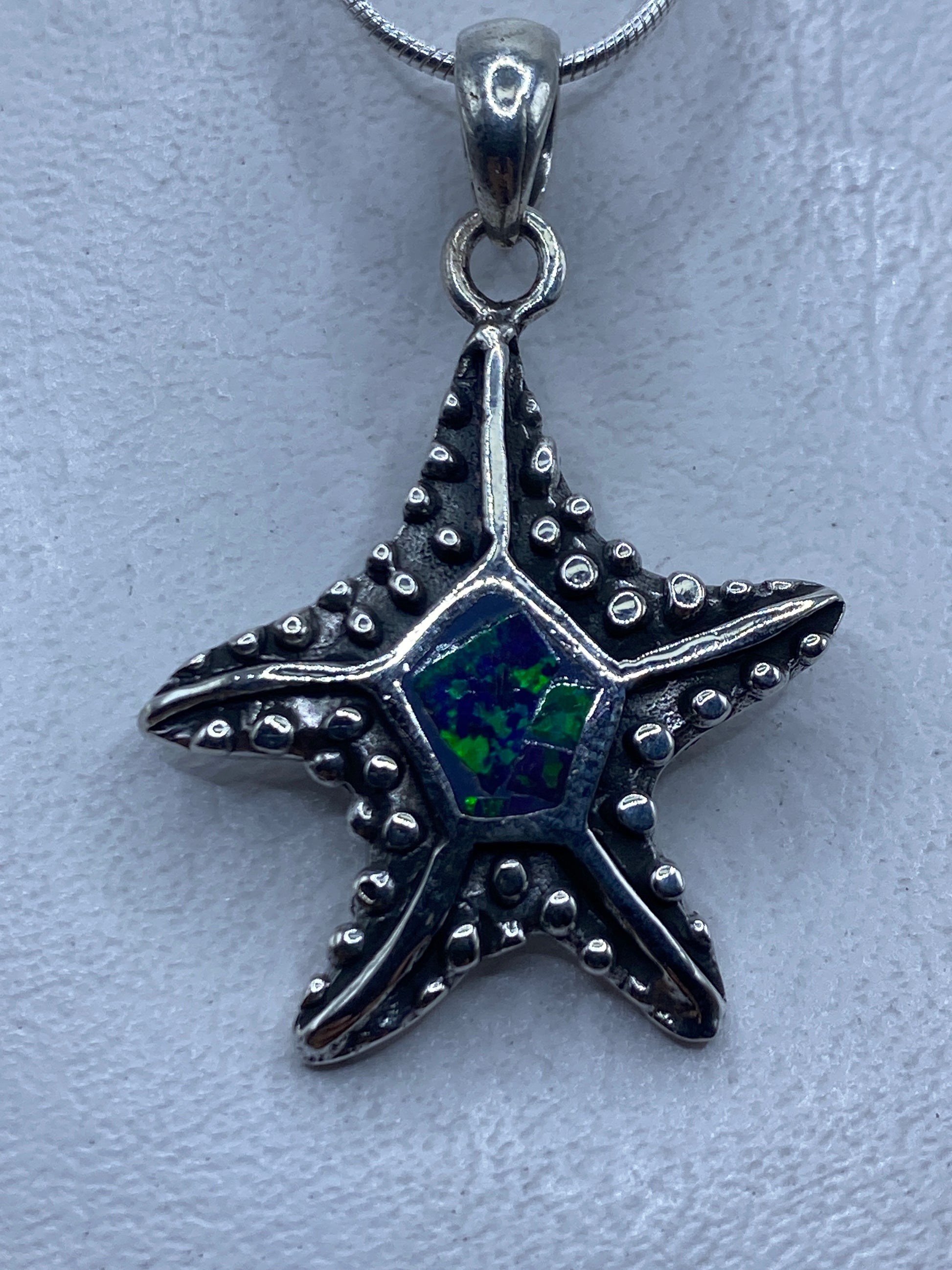 Dije estrella de plata con ópalo de fuego azul, colgando de cadena de eslabones