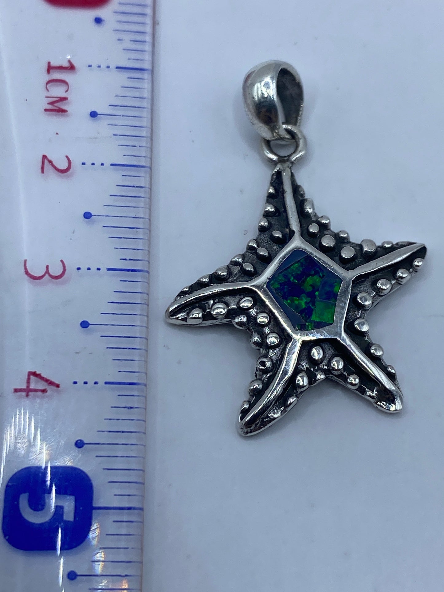 Detalle de la incrustación a mano del ópalo azul en la estrella de plata