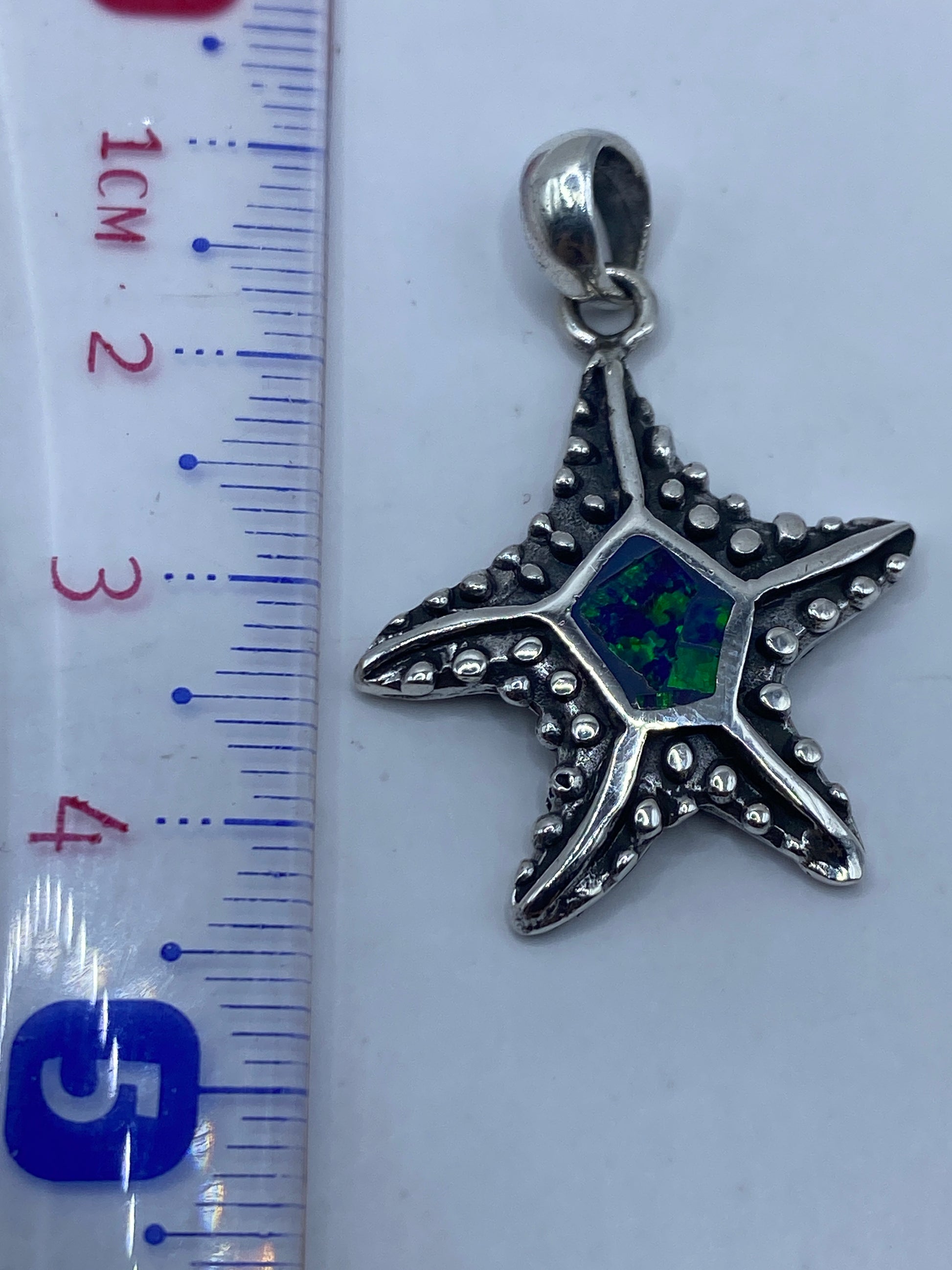Detalle de la incrustación a mano del ópalo azul en la estrella de plata