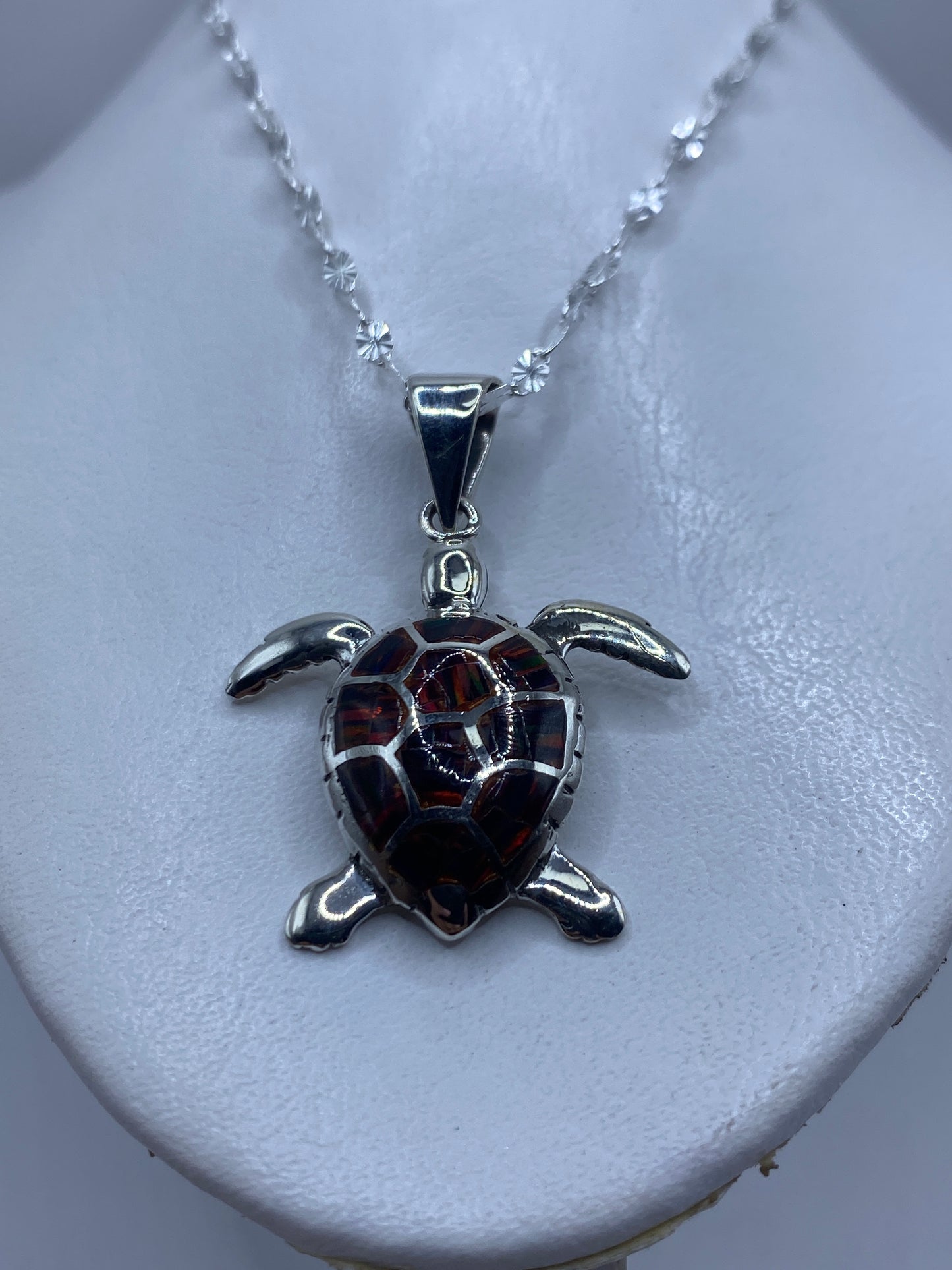 Detalle frontal de la tortuga: caparazón con ópalo de fuego y patas en plata pulida
