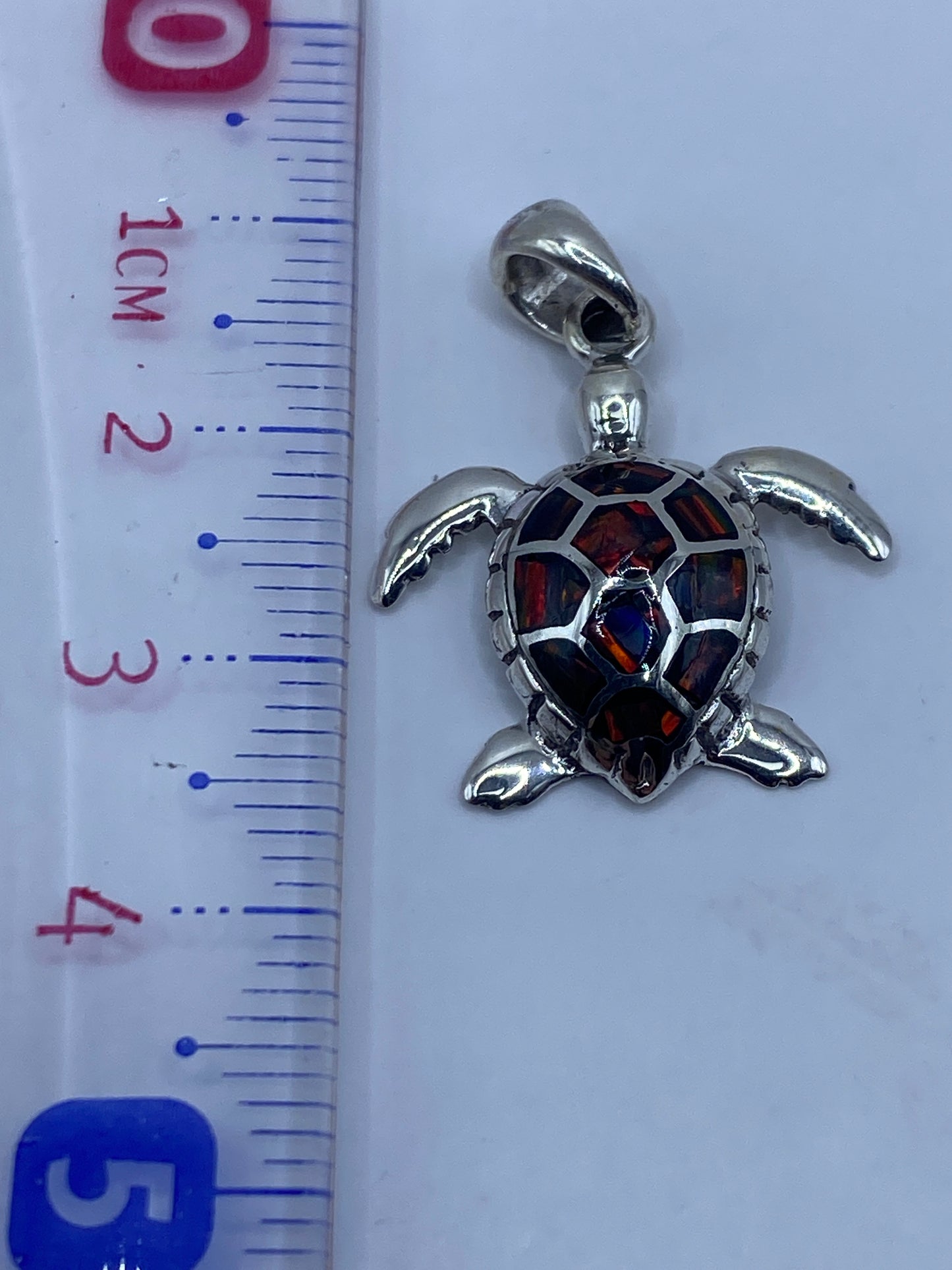 Dije de tortuga en plata pura pesado en báscula de precisión mostrando 2.9 gramos