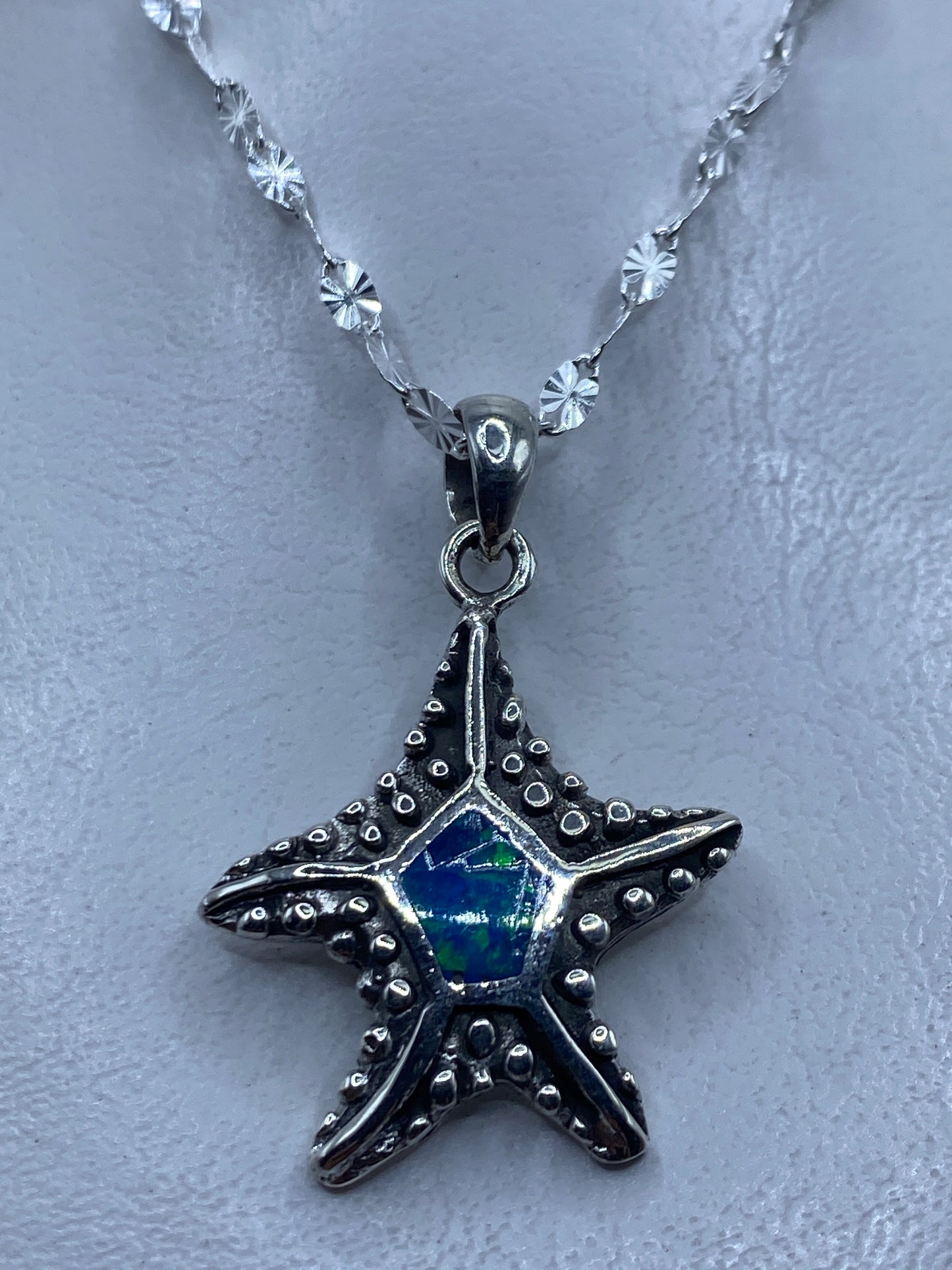 Dije de estrella de mar en plata .950 con ópalo de fuego azul colgando de cadena de eslabones pequeños