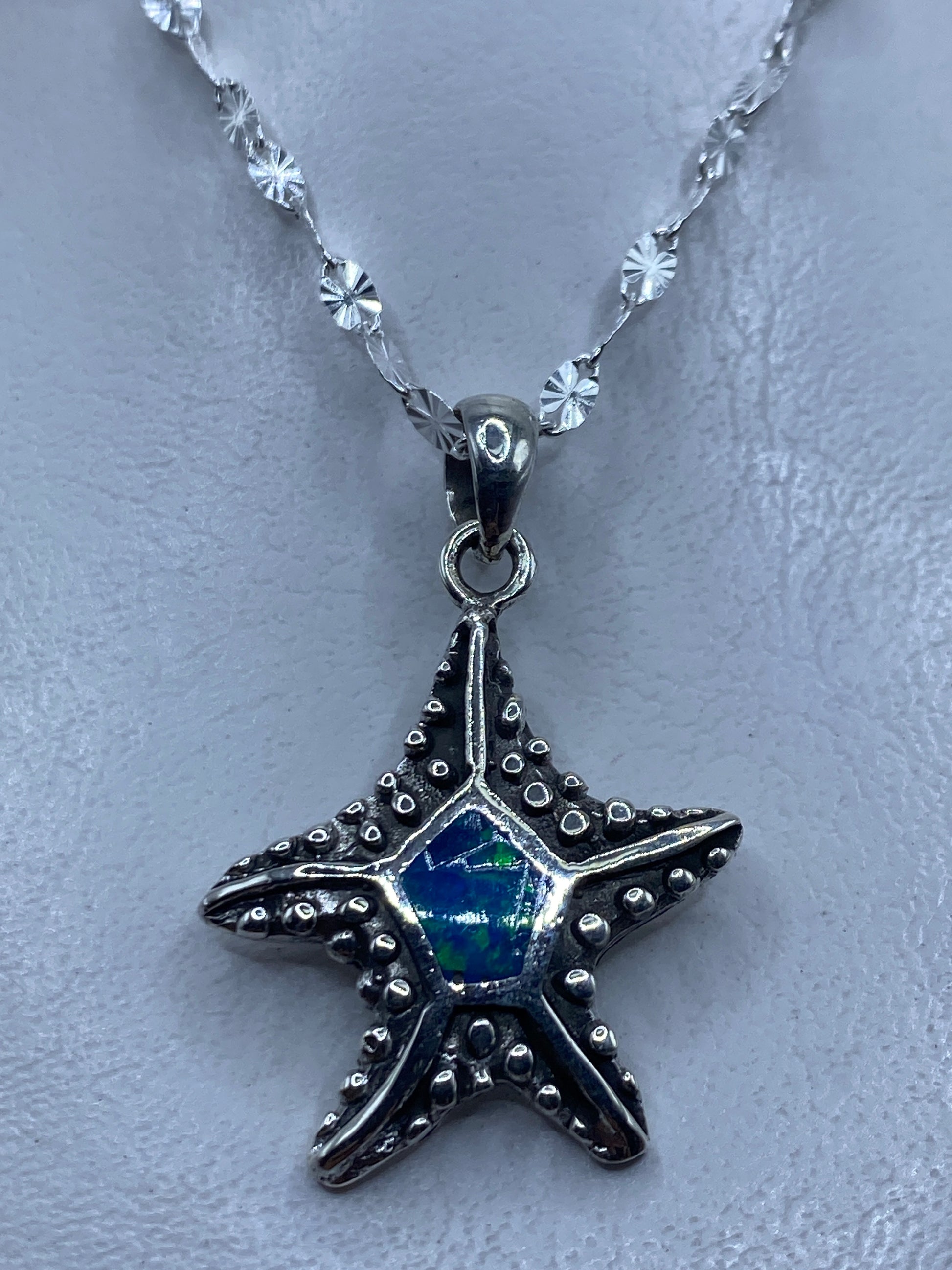 Dije de estrella de mar en plata .950 con ópalo de fuego azul colgando de cadena de eslabones pequeños