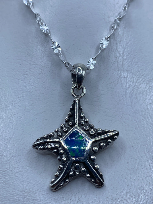 Dije de estrella de mar en plata .950 con ópalo de fuego azul colgando de cadena de eslabones pequeños