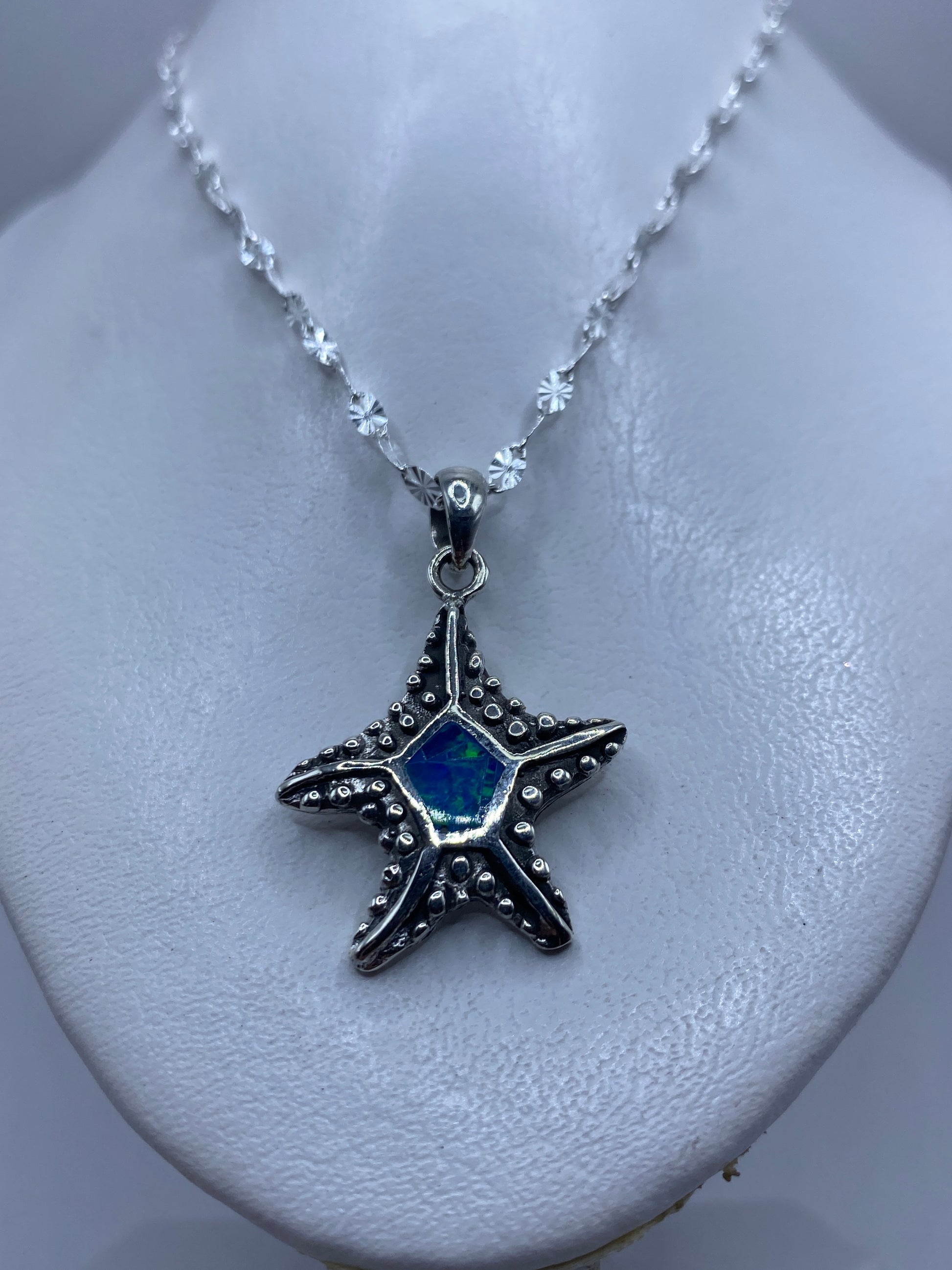 Estrella de mar vista de frente mostrando el ópalo azul engastado en el centro y el granulado artesanal