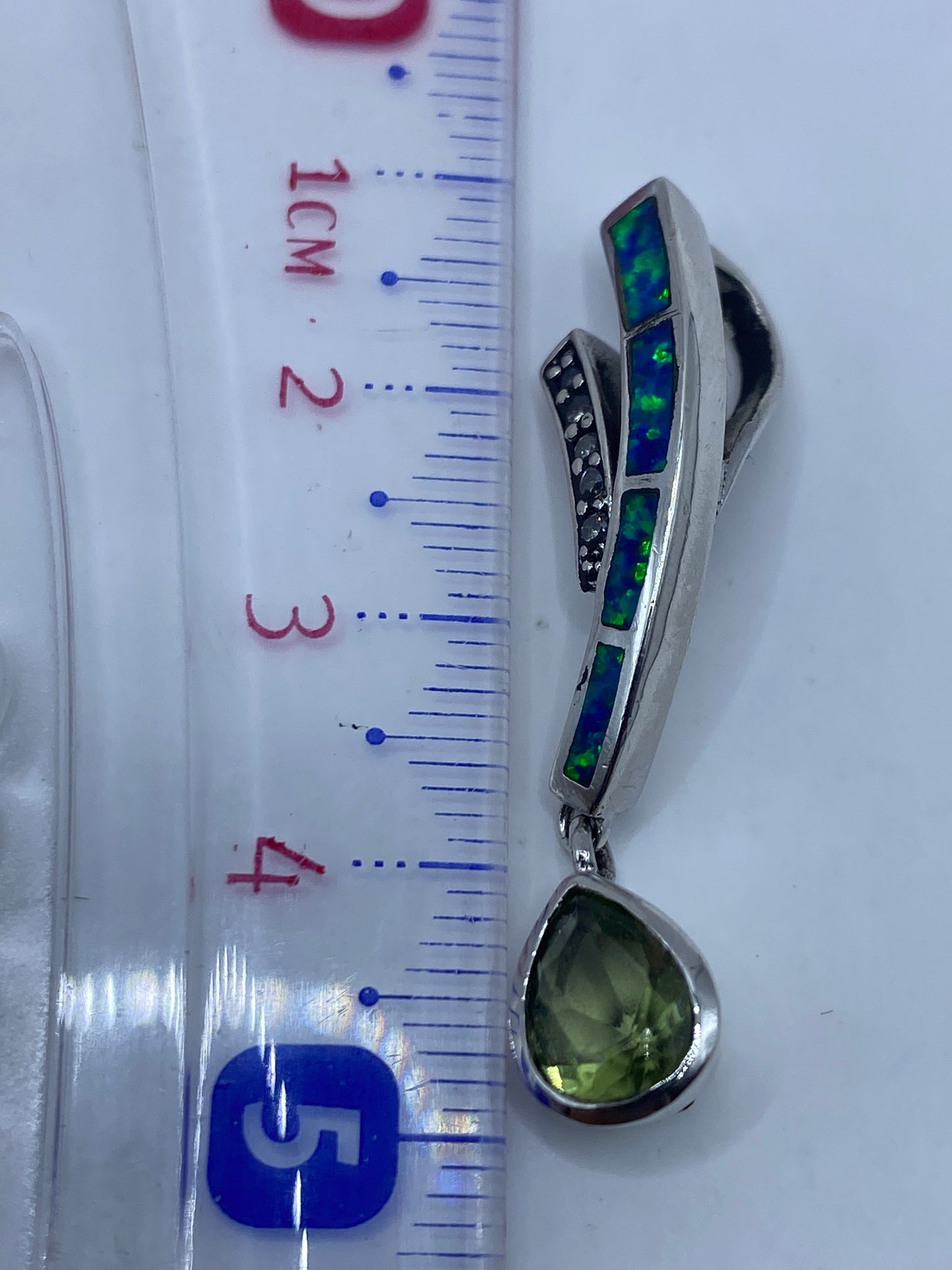 Dije sobre la piel mostrando el tamaño real de 4.6 cm y el tono azul del Ópalo